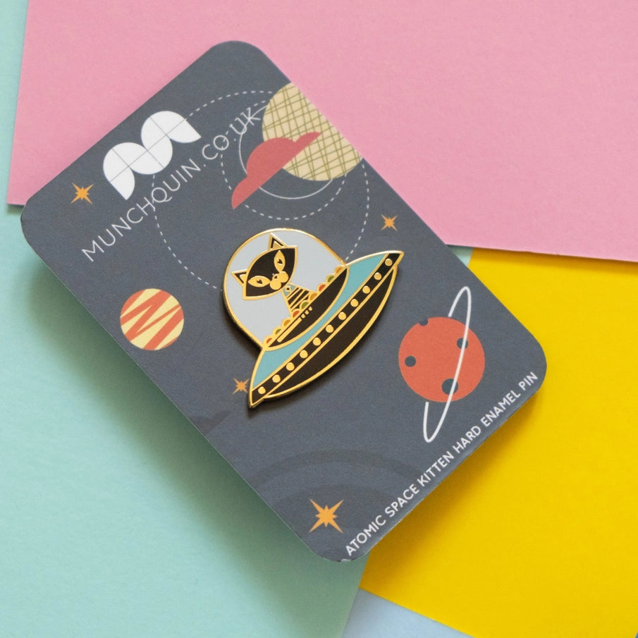 Munchquin Atomic Space Kitten Hard Enamel Pin - a quirky and fun enamel pin badge featuring a quirky black cat flying on a spaceship!