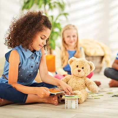 The game encourages children to create a cafe scene using their own teddies, dolls and toys. After they have done this, they must use their role play skills to add up the coins to match the price of a meal and serve it to the correct customer. The player to serve all their meals first wins!