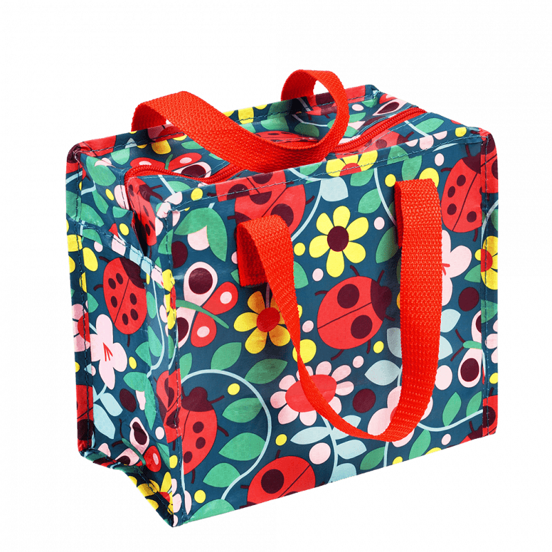 This fabulous Ladybird design Charlotte Bag features a colourful ladybird and flower design on a dark blue background with bright red handles. Say It Baby Gifts